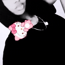 a person wearing a black shirt and a hello kitty necklace