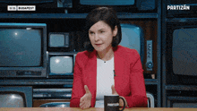a woman in a red jacket is sitting at a table with a mug that says partizn on it