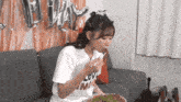 a girl wearing a white shirt that says love on it is eating a meal