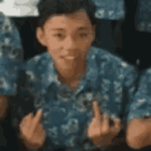 a boy in a blue shirt is giving the middle finger