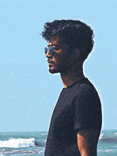 a man wearing sunglasses and a black shirt is standing on the beach