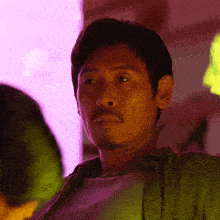 a man with a beard and a green shirt is looking at the camera