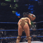 two women are wrestling in a ring and one of them is wearing a gold outfit