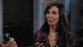 a man holding a glass of wine talks to a woman in front of a painting of birds