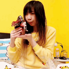 a girl in a yellow sweater is holding a figurine
