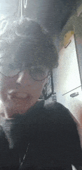 a young man wearing glasses and a black shirt makes a funny face