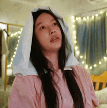 a woman wearing a pink shirt has a white cloth on her head
