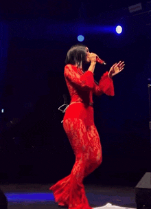 a woman in a red dress is singing into a microphone on stage