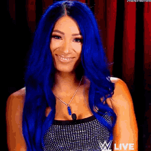 a woman with blue hair is smiling and wearing a necklace with the word live on it