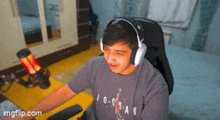 a young man wearing headphones is sitting in a chair in front of a computer .