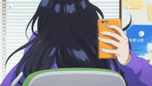 a person holding a cell phone in front of a board with chinese writing on it