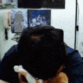 a man sitting in front of a tv with a cat on his shoulder