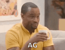 a man is sitting on a couch holding a cup of coffee and saying ag .