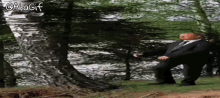 a man in a suit and tie is standing in the woods