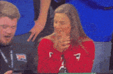 a man and a woman are sitting in a stadium and the woman is wearing a red sweater with the letter a on it