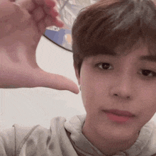 a close up of a young man making a heart shape with his hand .