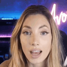 a close up of a woman 's face with a neon sign in the background