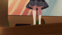 a girl in a plaid skirt and white socks is standing on a wooden ledge