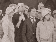 a man in a suit stands in a crowd of people