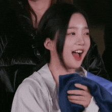 a woman is holding a blue towel around her neck while smiling .