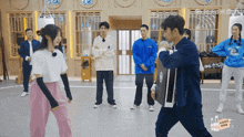 a group of people are standing in a room and one of them is wearing a shirt that says ' a ' on it