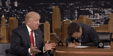 a man in a suit and tie is laughing while sitting next to another man in a suit and tie