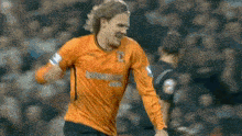 a soccer player wearing an orange jersey that says ' airways ' on it