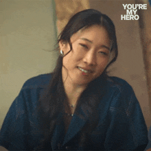 a woman in a blue shirt is smiling with the words you 're my hero behind her