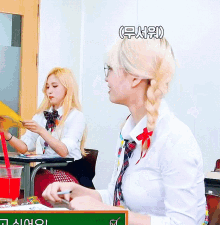 a girl in a plaid tie sits at a desk in front of a chalkboard that says ' a ' on it