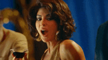 a woman is laughing while holding a drink in her hand