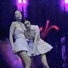 two women in white dresses are dancing on a stage in front of purple lights .