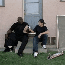 two men are sitting on the steps of a house talking
