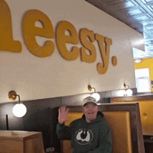 a man in a green bay packers sweatshirt stands in front of a wall that says leesy