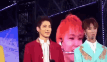 a group of young men are standing on a stage in front of a large screen with a woman 's face on it .