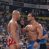 two men wrestling in front of a crowd with a fly emirates sign above them
