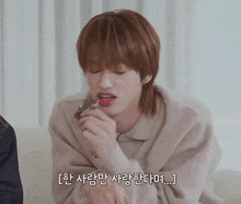 a young man with korean writing on his face is applying lipstick to his lips
