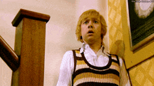a man standing on a set of stairs wearing a striped vest