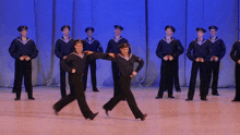 a group of men in navy uniforms are dancing on stage