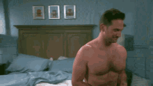 a shirtless man is standing in a bedroom next to a lamp and a door .