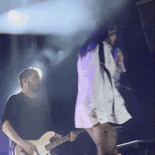 a man is playing a guitar while a woman sings on stage