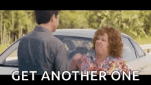 a man and a woman are standing next to each other in front of a car and the woman is yelling at the man .