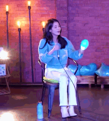 a woman in a blue sweater is sitting in a chair holding a microphone