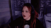 a woman with red hair is wearing headphones and a black shirt while playing a video game .