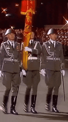 three men in military uniforms marching with a flag that says ' germany ' on it
