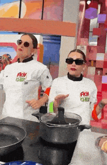two women wearing floy chef shirts are standing next to each other in a kitchen