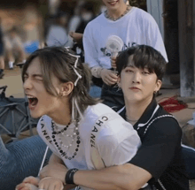 a man wearing a chanel shirt is hugging a woman