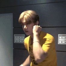 a man in a yellow shirt is standing in front of a wall with a sign that says ' a ' on it