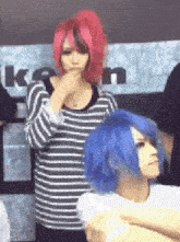 a woman with red hair and a blue wig is standing next to a woman with blue hair .