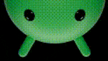 a close up of a green object with black eyes on a black background