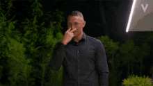 a man wearing a black shirt is covering his nose with his hand